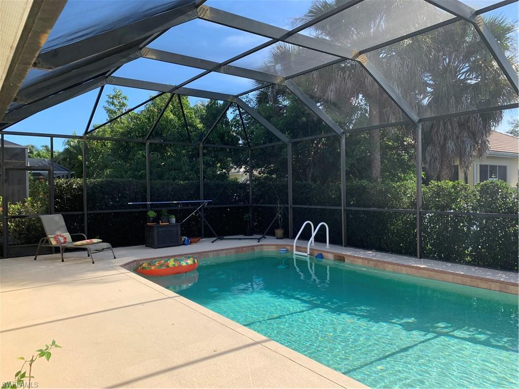 8267 Laurel Lakes Way Naples, FL 34119 - Photo 22 of 23 Swimming pool featuring glass enclosure, a sunroom, and a patio