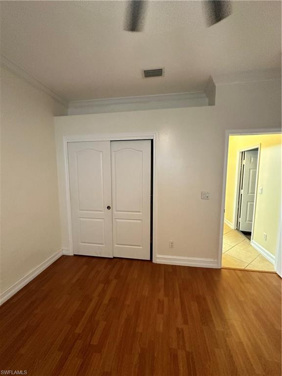 8267 Laurel Lakes Way Naples, FL 34119 - Photo 4 of 23 Unfurnished bedroom featuring ornamental molding, wood finished floors, a textured ceiling, a closet, and ceiling fan