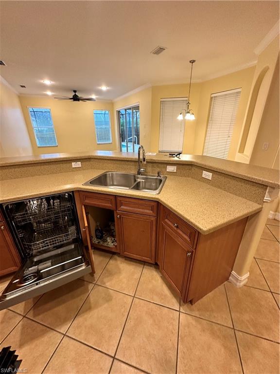 8267 Laurel Lakes Way Naples, FL 34119 - Photo 10 of 23 Kitchen featuring ornamental molding, brown cabinets, light tile patterned floors, decorative light fixtures, and dishwashing machine
