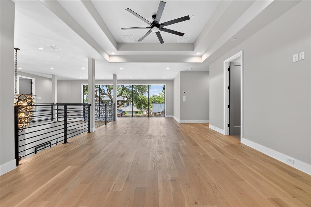 11028 Edgemere Road Dallas, TX 75230 - Photo 29 of 40 Spacious upper-level area featuring light wood-finish flooring and a tray ceiling with a contemporary ceiling fan