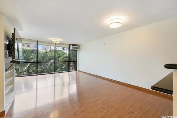 a view of an empty room with wooden floor and a window