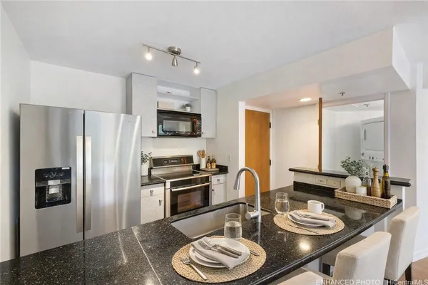 a kitchen with a refrigerator a stove a sink and chairs