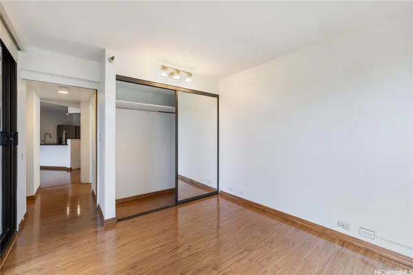 a view of empty room with wooden floor and fan