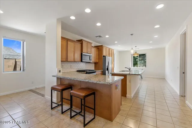 a kitchen with kitchen island granite countertop wooden cabinets a counter top space and stainless steel appliances
