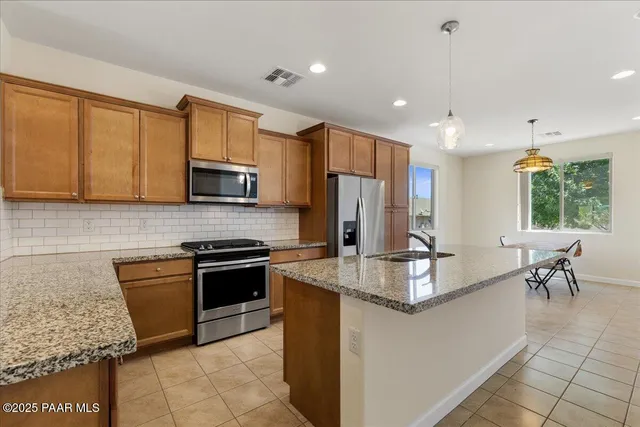 a kitchen with stainless steel appliances granite countertop a stove refrigerator sink and cabinets