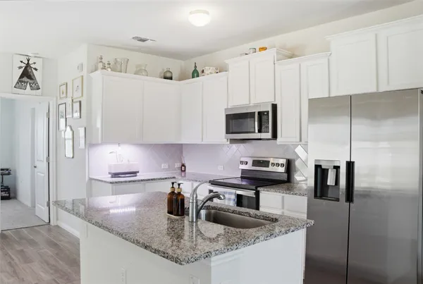 a open kitchen with white cabinets and stainless steel appliances