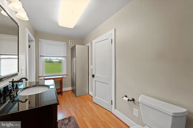 a spacious bathroom with a granite countertop sink a toilet a mirror and shower