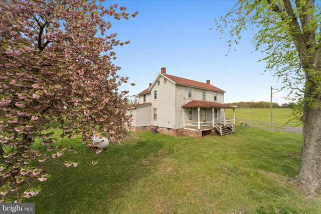 a view of a large white house with a big yard and large trees