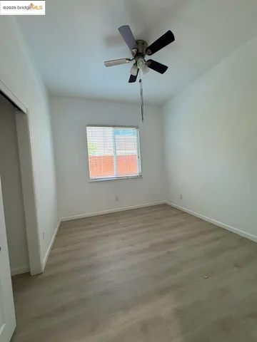 an empty room with wooden floor ceiling fan and windows