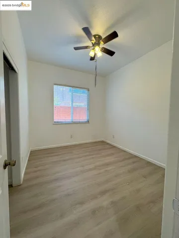 an empty room with wooden floor fan and windows