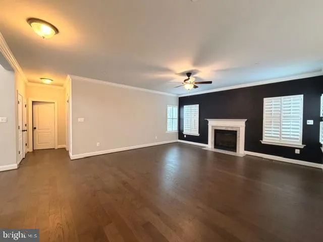 an empty room with wooden floor fireplace and windows