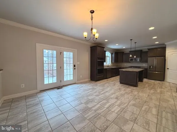 a large kitchen with kitchen island granite countertop a refrigerator a oven a sink and a large window