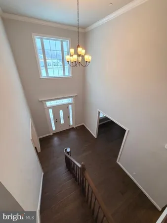 a view of an empty room with chandelier fan and wooden floor