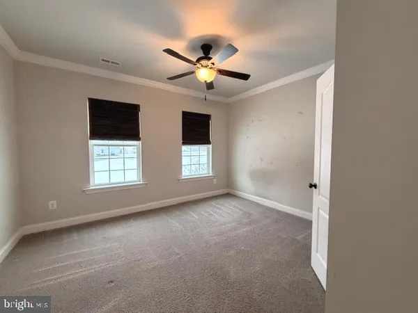 a view of an empty room with window and chandelier fan