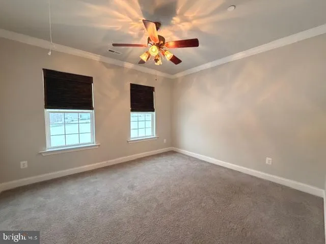 an empty room with windows and chandelier fan