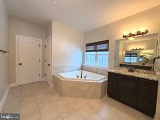 a spacious bathroom with a bathtub sink and mirror