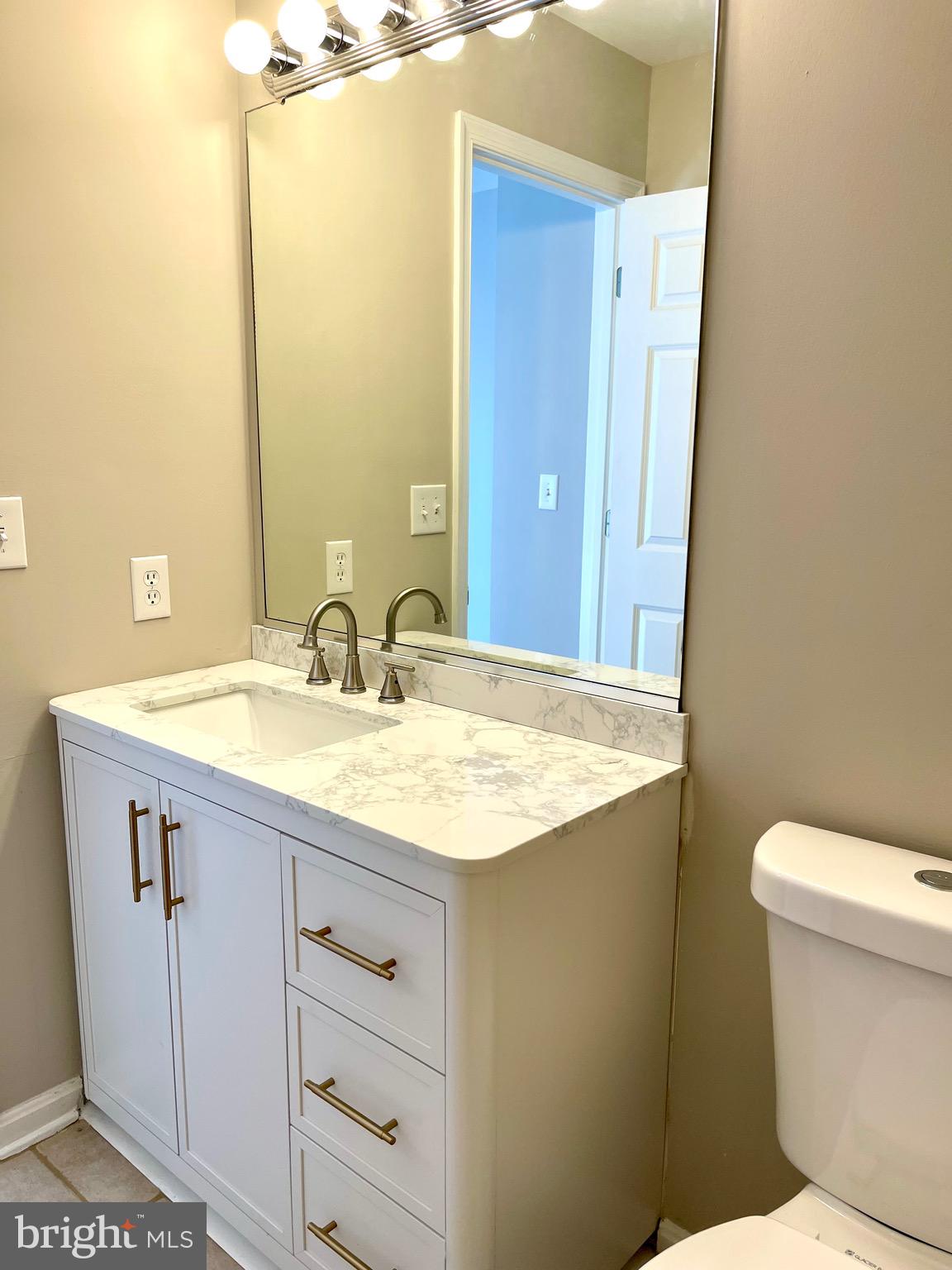 12003 Piscataway Road Clinton, MD 20735 - Photo 35 of 68 a bathroom with a granite countertop sink a toilet and a mirror