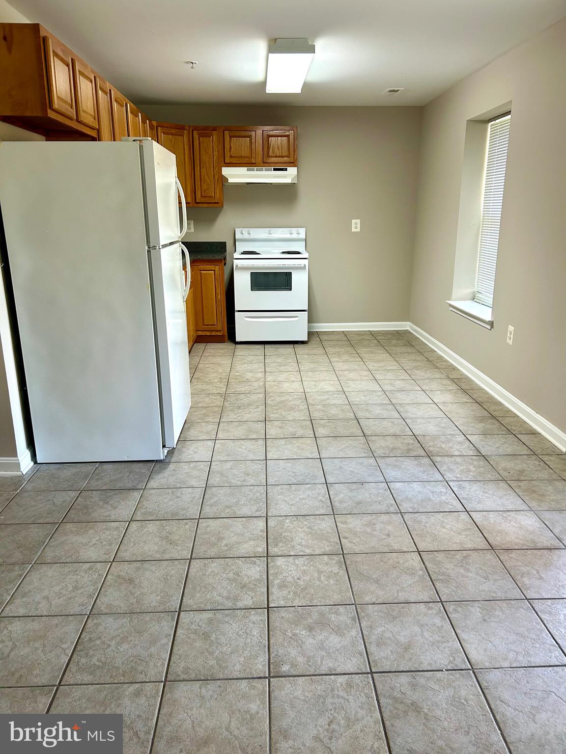 12003 Piscataway Road Clinton, MD 20735 - Photo 51 of 68 a view of a refrigerator in kitchen and an empty room in wooden floor