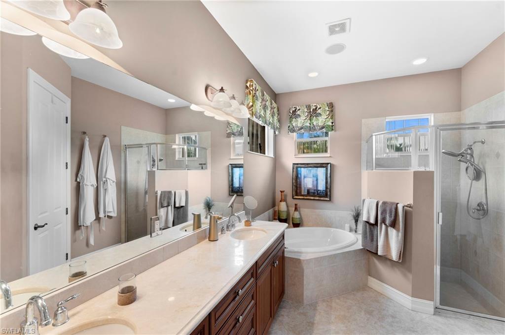 6155 Dogleg Drive Naples, FL 34113 - Photo 14 of 36 a spacious bathroom with a double vanity sink a large mirror a bathtub and shower