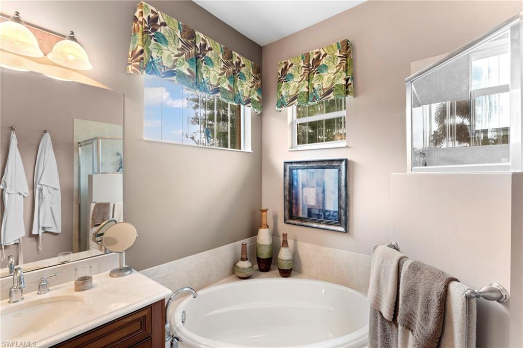 6155 Dogleg Drive Naples, FL 34113 - Photo 15 of 36 a bathroom with a granite countertop double vanity sink a mirror and a bathtub