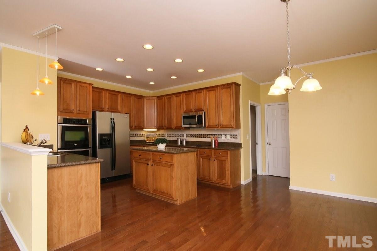 832 Seastone Street Raleigh, NC 27603 - Photo 6 of 25 a kitchen with refrigerator cabinets and wooden floor