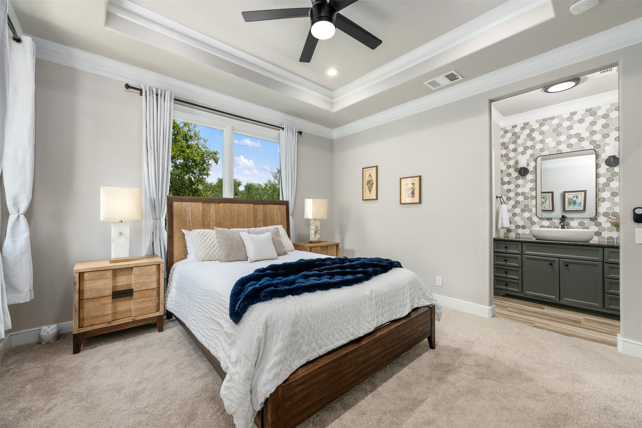 10716 Beach Road Leander, TX 78641 - Photo 20 of 39 Bedroom featuring a tray ceiling, ornamental molding, light colored carpet, connected bathroom, and ceiling fan