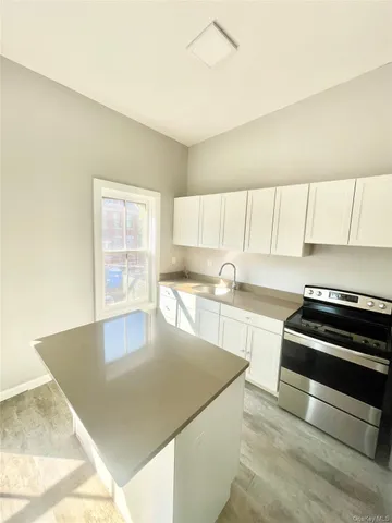 a kitchen with stainless steel appliances a stove a sink and white cabinets