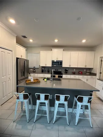a kitchen with stainless steel appliances granite countertop a table chairs sink refrigerator and cabinets