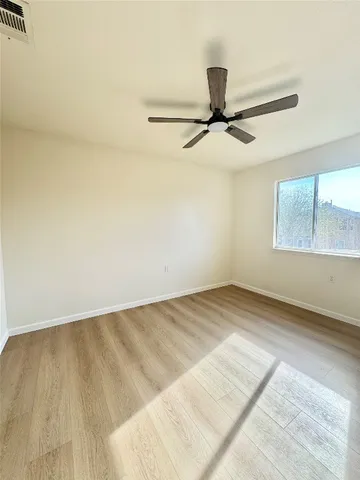 an empty room with a window and a ceiling fan