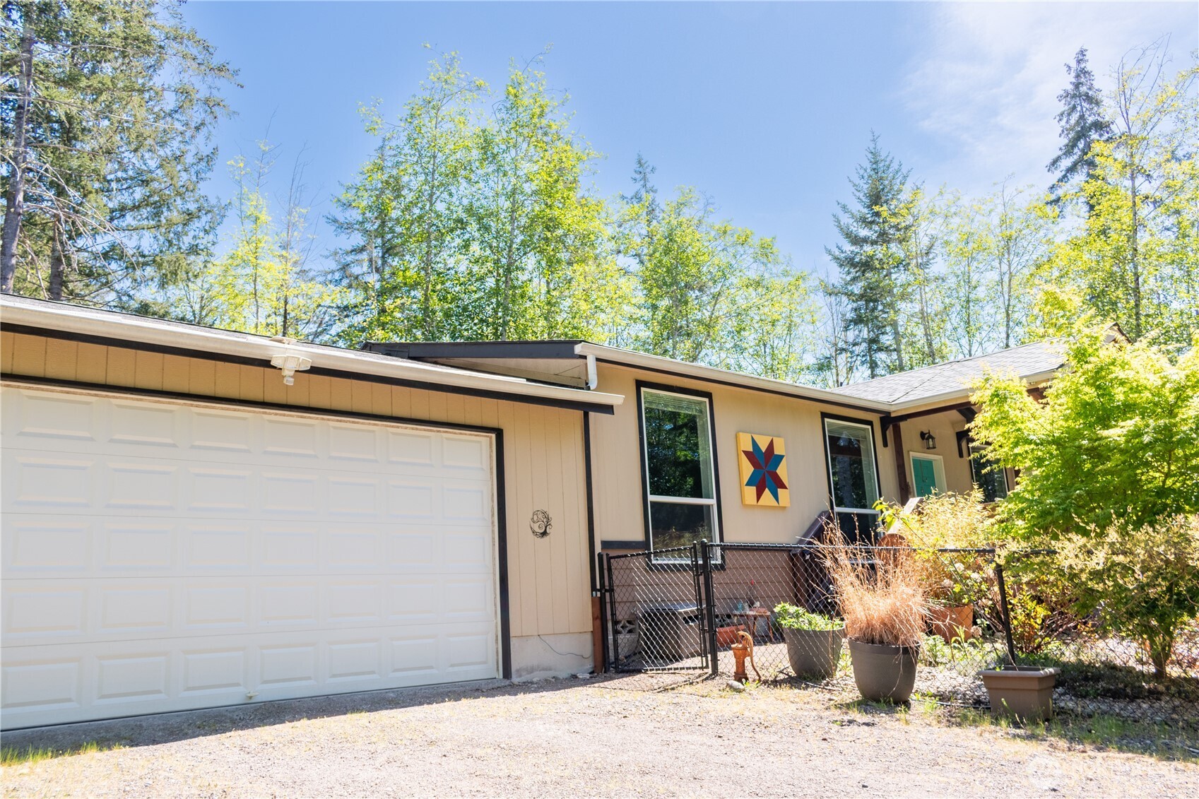 3111 East Rasor Road Belfair, WA 98528 - Photo 2 of 26 a view of a house with potted plants and large trees