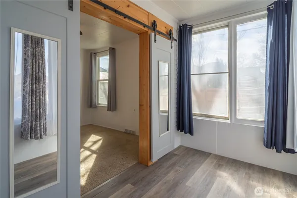 a view of an empty room with wooden floor and a window