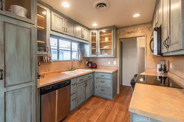 a kitchen with stainless steel appliances a stove a sink dishwasher and cabinets with wooden floor