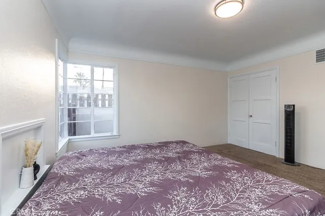 a bedroom with a bed a table and windows