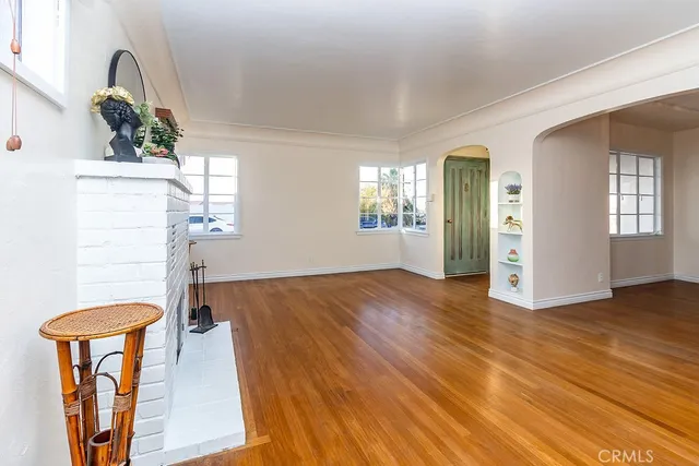 an empty room with wooden floor chandelier and windows