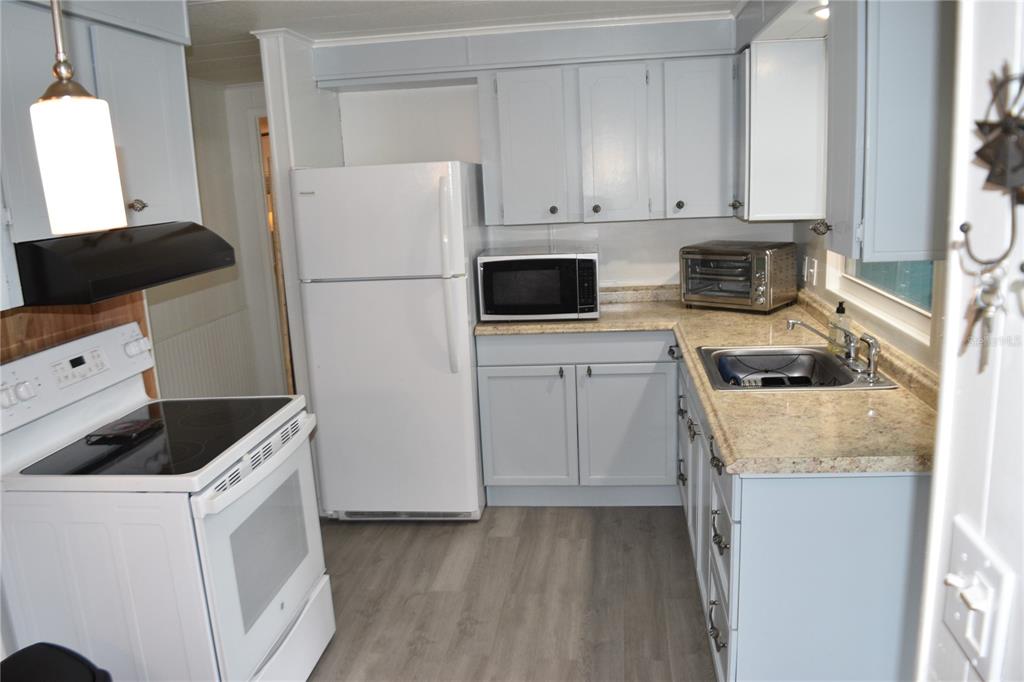 4407 Tucker Square New Port Richey, FL 34652 - Photo 27 of 69 a kitchen with a refrigerator stove and white cabinets
