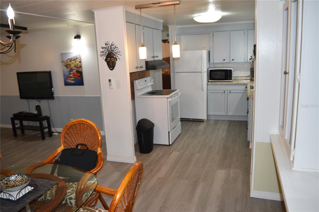 4407 Tucker Square New Port Richey, FL 34652 - Photo 33 of 69 a kitchen with stainless steel appliances a microwave a stove a refrigerator a sink a dining table and chairs with wooden floor