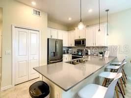 707 Ocean Course Avenue Davenport, FL 33896 - Photo 15 of 31 a kitchen with a refrigerator a stove a sink and a dining table with wooden floor