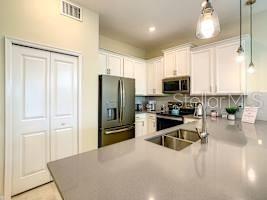 707 Ocean Course Avenue Davenport, FL 33896 - Photo 9 of 31 a kitchen with stainless steel appliances a refrigerator a stove a sink and a microwave