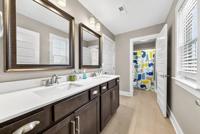 a en suite bathroom with a double vanity sink a mirror and next to a window