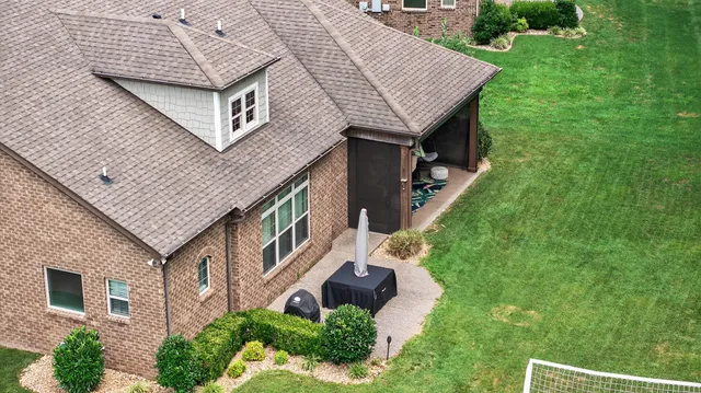 a aerial view of a house next to a big yard and large tree