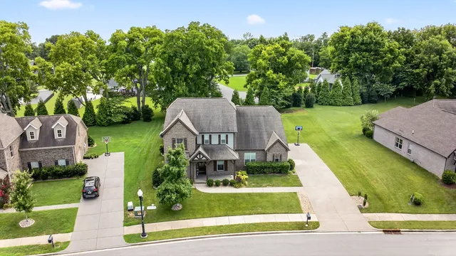 a aerial view of a house next to a big yard and large trees