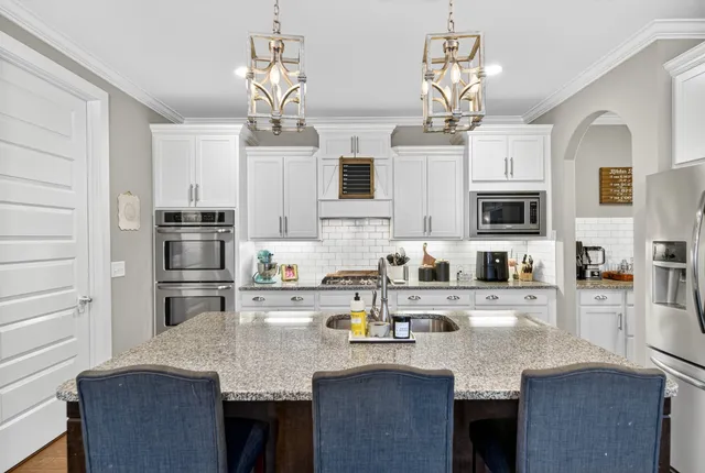 a kitchen with stainless steel appliances granite countertop a sink dishwasher stove refrigerator and microwave with wooden floor