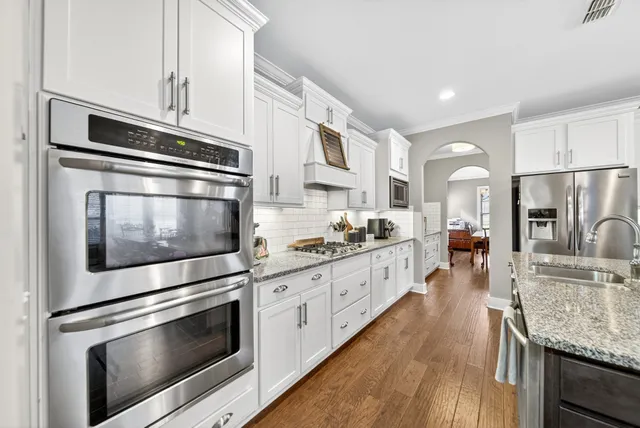 a kitchen with stainless steel appliances white cabinets a stove a sink and a refrigerator