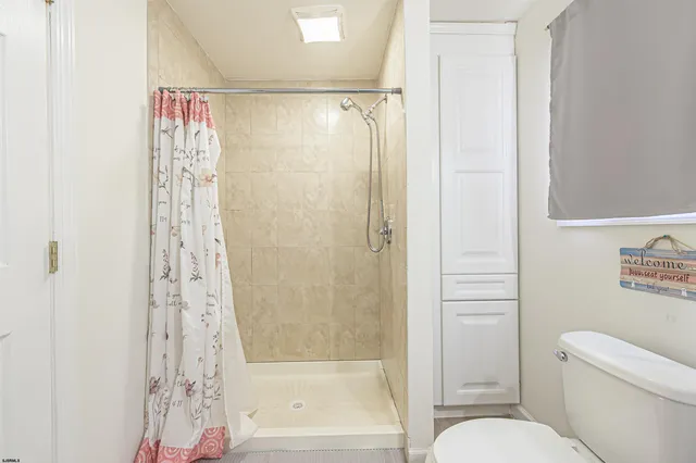 a bathroom with a shower curtain a toilet and a shower