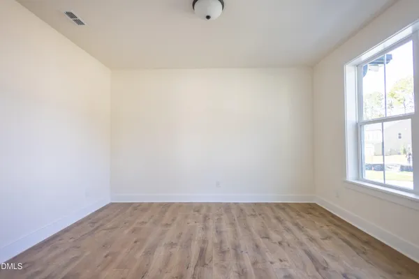 an empty room with wooden floor windows and ceiling fan