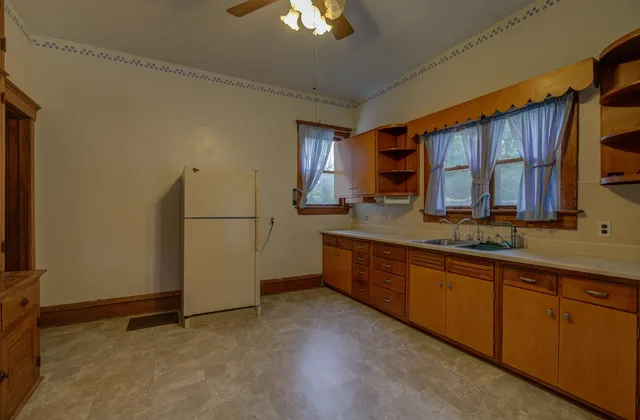 a kitchen with stainless steel appliances granite countertop a refrigerator a sink dishwasher and wooden cabinets with wooden floor