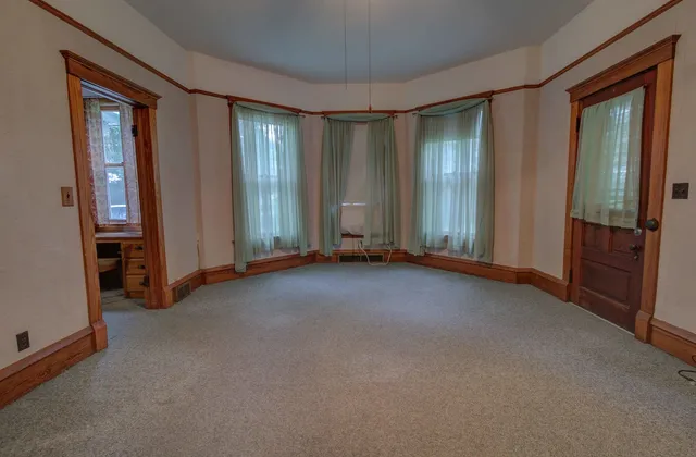 an empty room with chandelier fan and windows