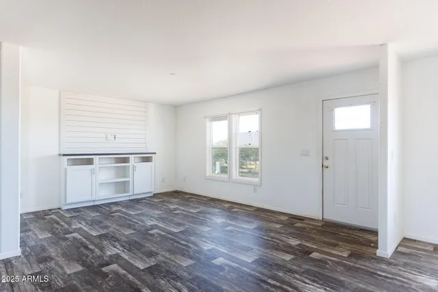a view of empty room with wooden floor and window