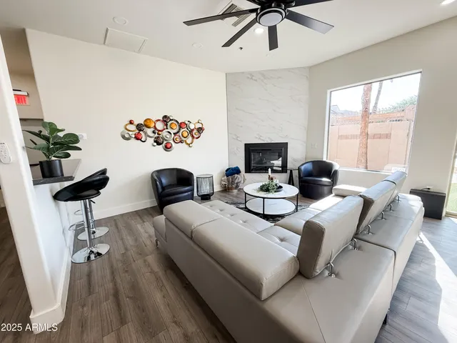 a living room with furniture kitchen view and a wooden floor