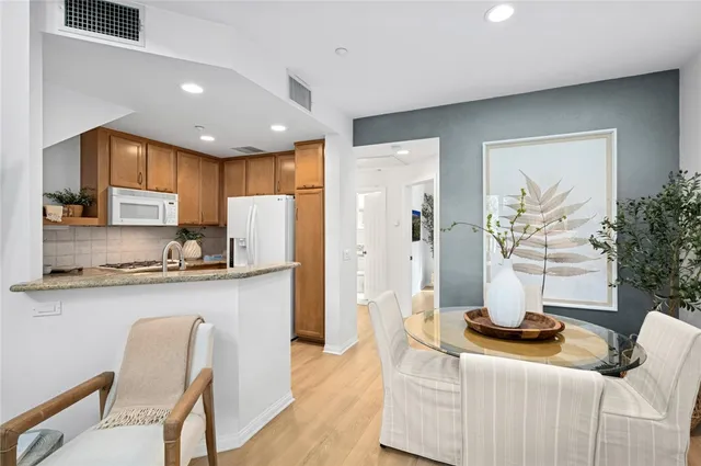 a kitchen with stainless steel appliances granite countertop a refrigerator a stove a sink dishwasher and white cabinets with wooden floor